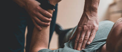 person receiving leg therapy with hands on muscles and joints focused on rehabilitation and physical therapy