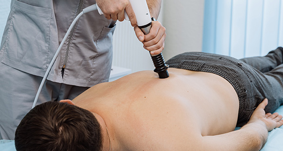 man receiving therapy treatment on back in medical setting with therapist using ultrasound device for pain relief and recovery three benefits of therapy